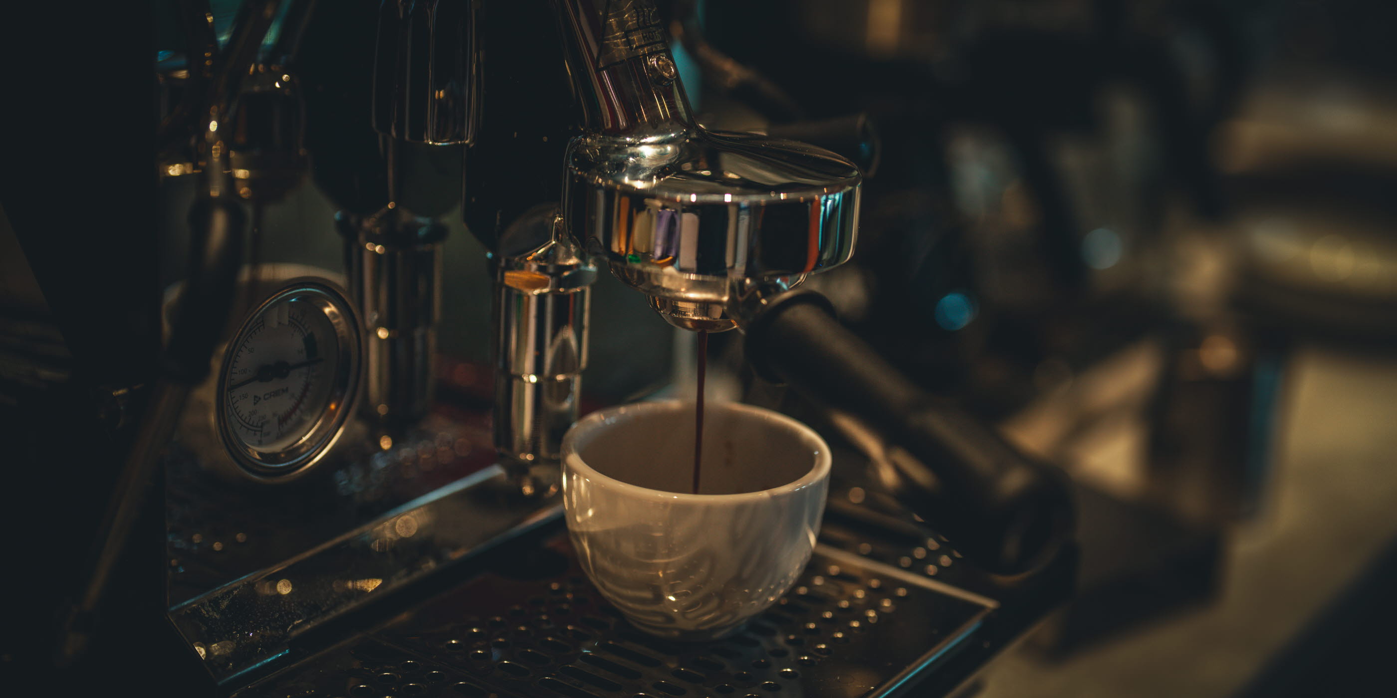 Espressomaskin i aktion som brygger kaffe ner i en vit kopp.