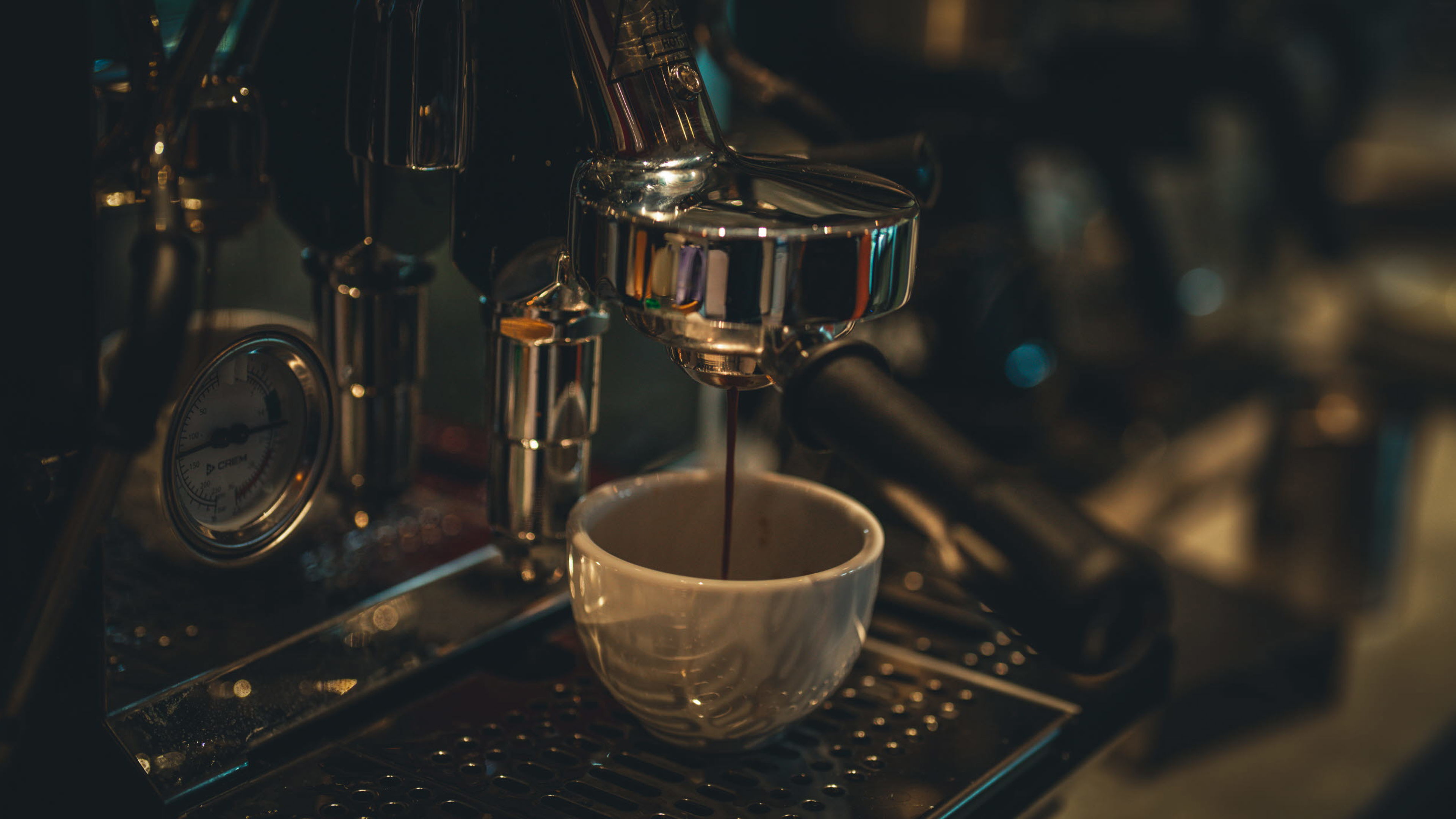 Espressomaskin i aktion som brygger kaffe ner i en vit kopp.